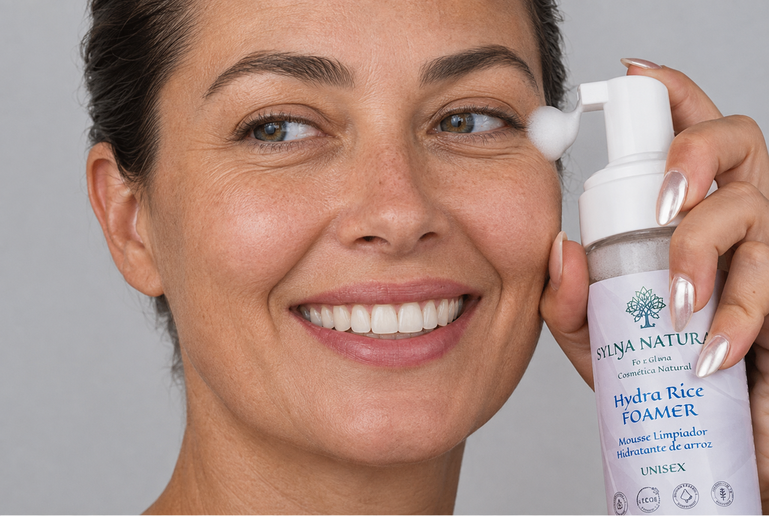 Mujer sonriendo mientras aplica el mousse limpiador Hydra Rice Foamer de SYLŊA NATURÆ